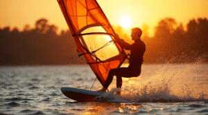 Windsurfingowy sprzęt na tle zachodzącego słońca, idealny do sportów wodnych i rekreacji na wodzie.